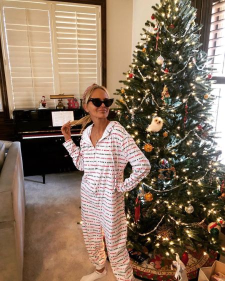 Kristin Chenoweth in her white night dress poses in front of  Christmas tree at her home.